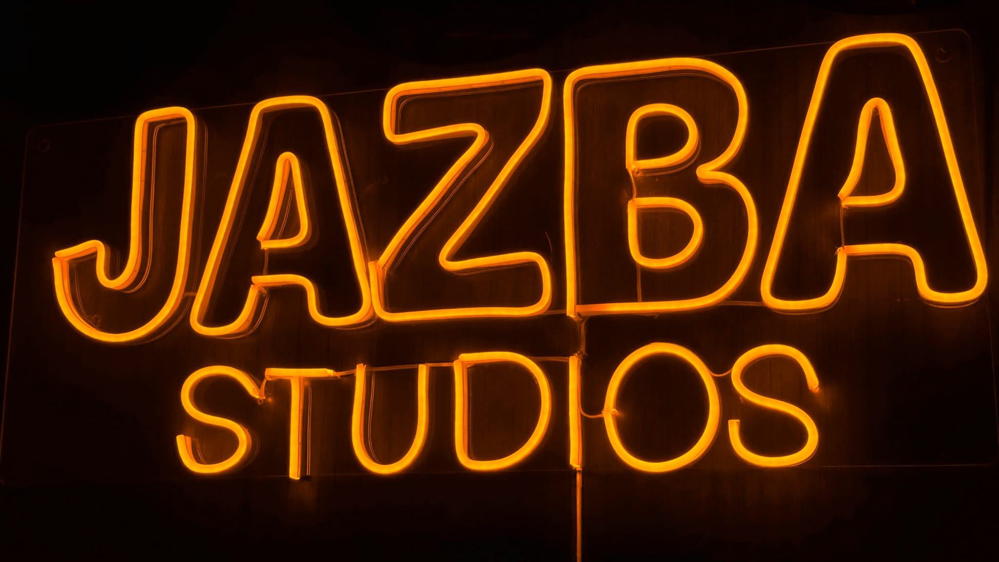 The Jazba Studios neon sign glowing on the studio wall
